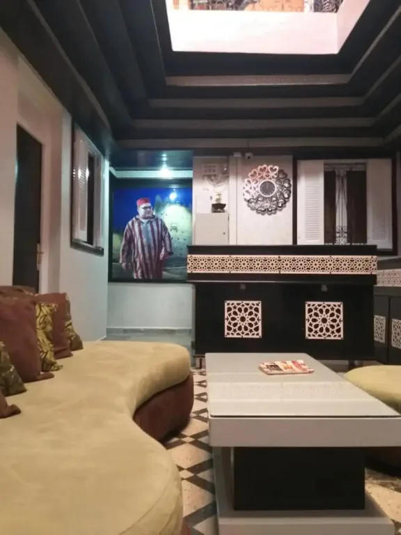 Salon du riad sous un puits de lumière, avec banquettes et motifs décoratifs